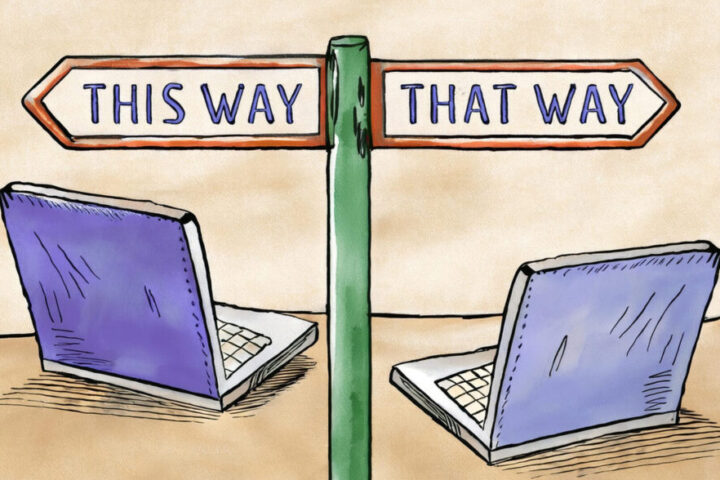 two laptops with street sign with arrow pointing two different ways